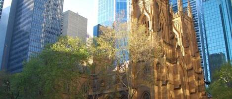 A historic building with Gothic architecture, surrounded by modern skyscrapers.