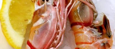 A plate of cooked shrimp on ice with a lemon wedge.