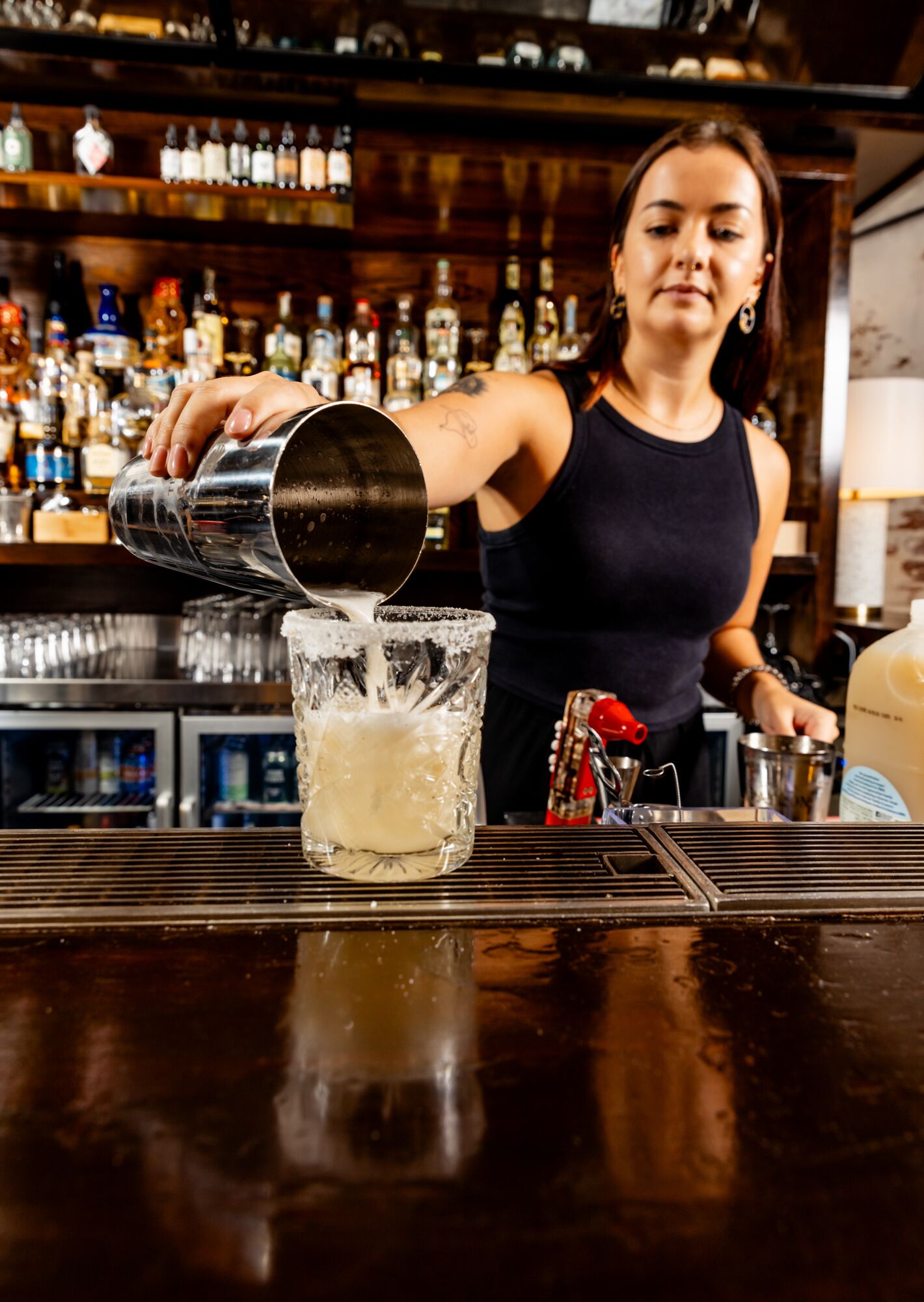 A bartender pouring a drink into a glass.