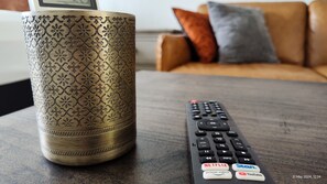 A remote control with buttons for Netflix, Prime Video, Stan, and YouTube, and a decorative vase on a table.