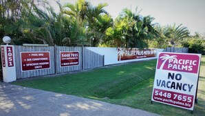 A sign for Pacific Palms with amenities including pool BBQ, air conditioning, and spacious modern units.