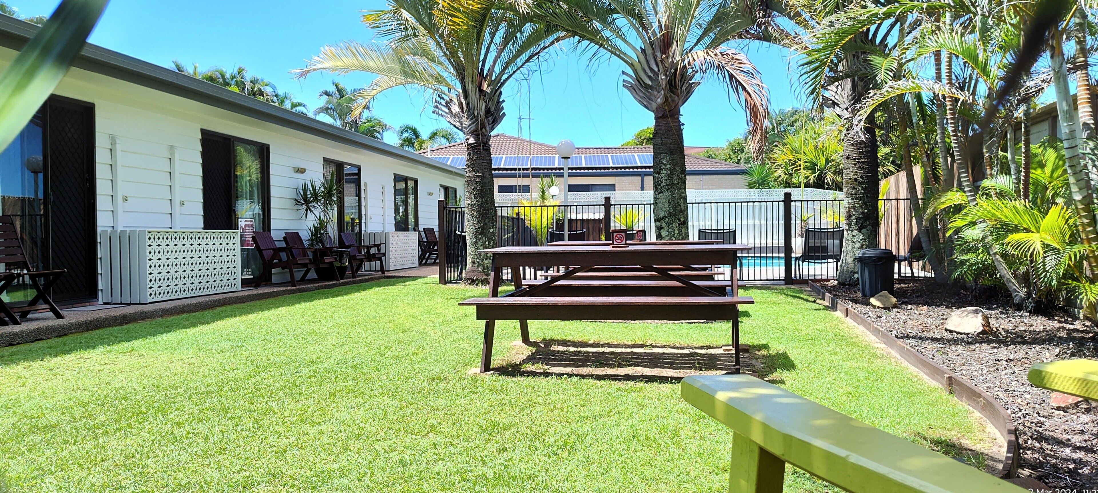 A courtyard with a picnic table, lounge chairs, and a pool area.
