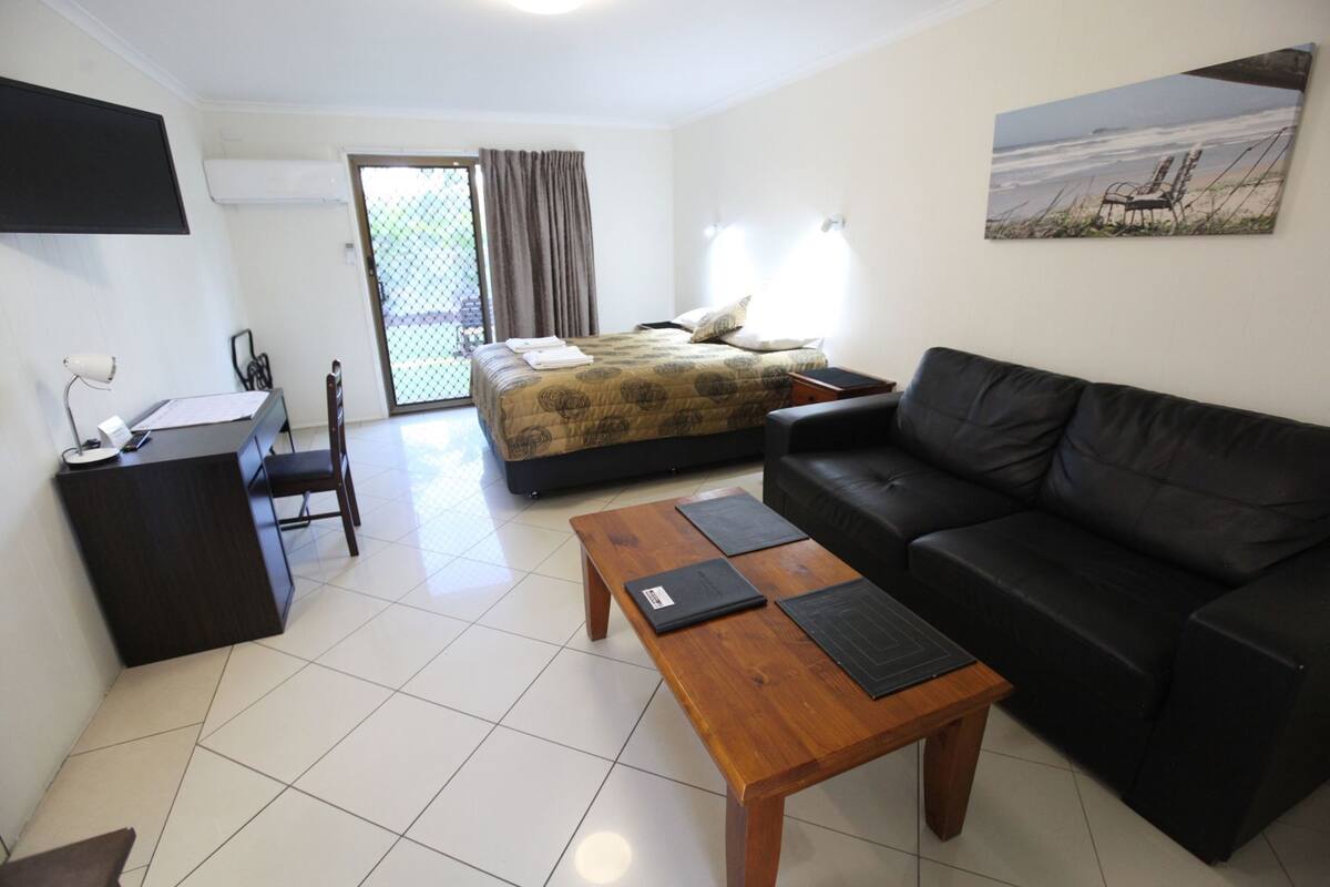 A hotel room with a bed, a sofa, a desk, and a coffee table.