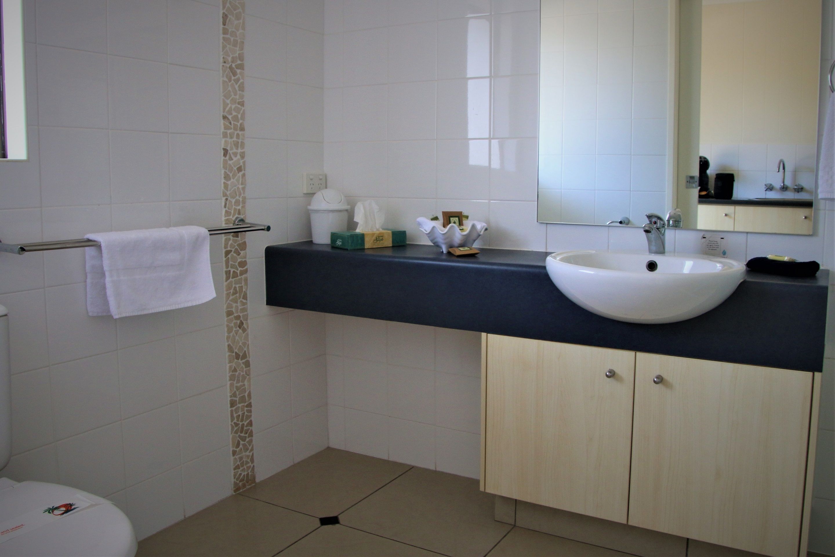 A bathroom with a white sink, a mirror, a towel rack, and a toilet.