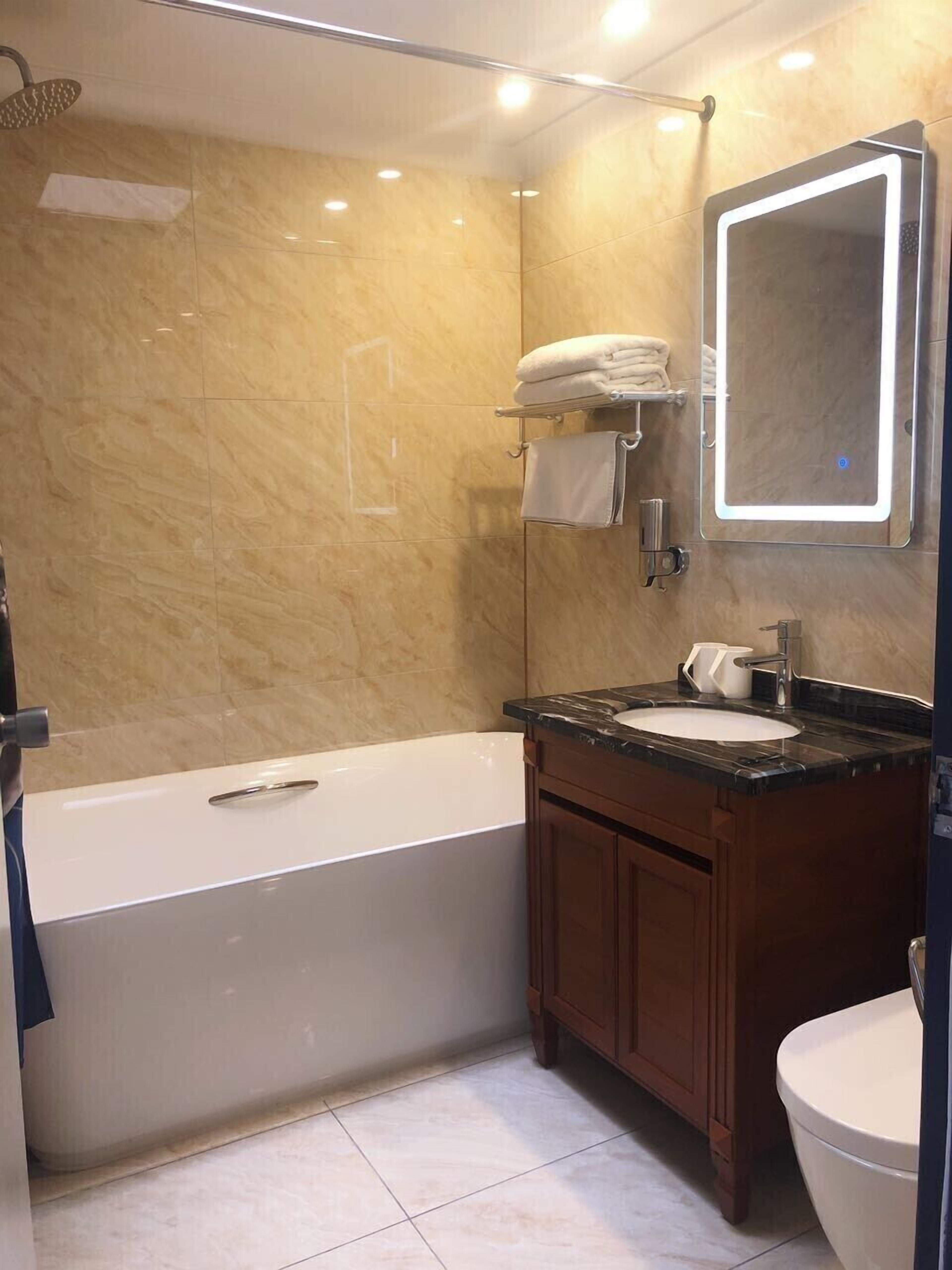 Une salle de bain moderne avec une baignoire, un meuble-lavabo et un grand miroir.