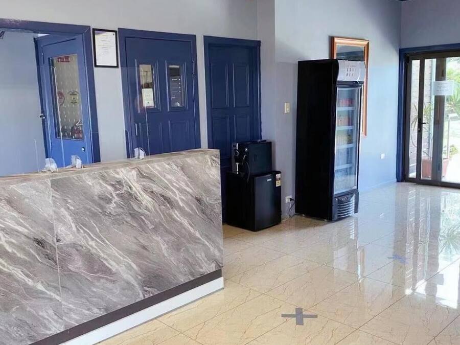 Uma área de recepção com balcão de mármore, portas azuis e um refrigerador.