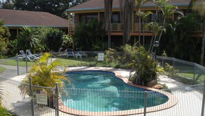 A swimming pool surrounded by a metal fence, with a building in the background. - Oxley Motor Inn (Oxley)