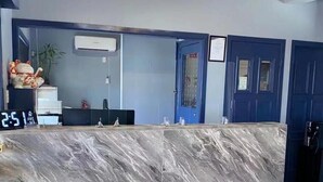 A reception desk with a marble top, a digital clock, and a blue door in the background. - Oxley Motor Inn (Oxley)