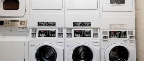 Une buanderie équipée de plusieurs machines à laver et de plusieurs séchoirs, notamment une machine à laver à chargement frontal et un sèche-linge à chargement par le haut.