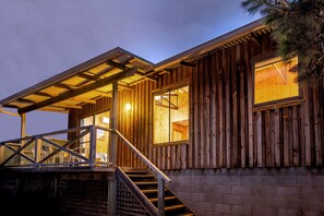 Una cabaña de madera con un porche cubierto, una escalera y un gran ventanal.