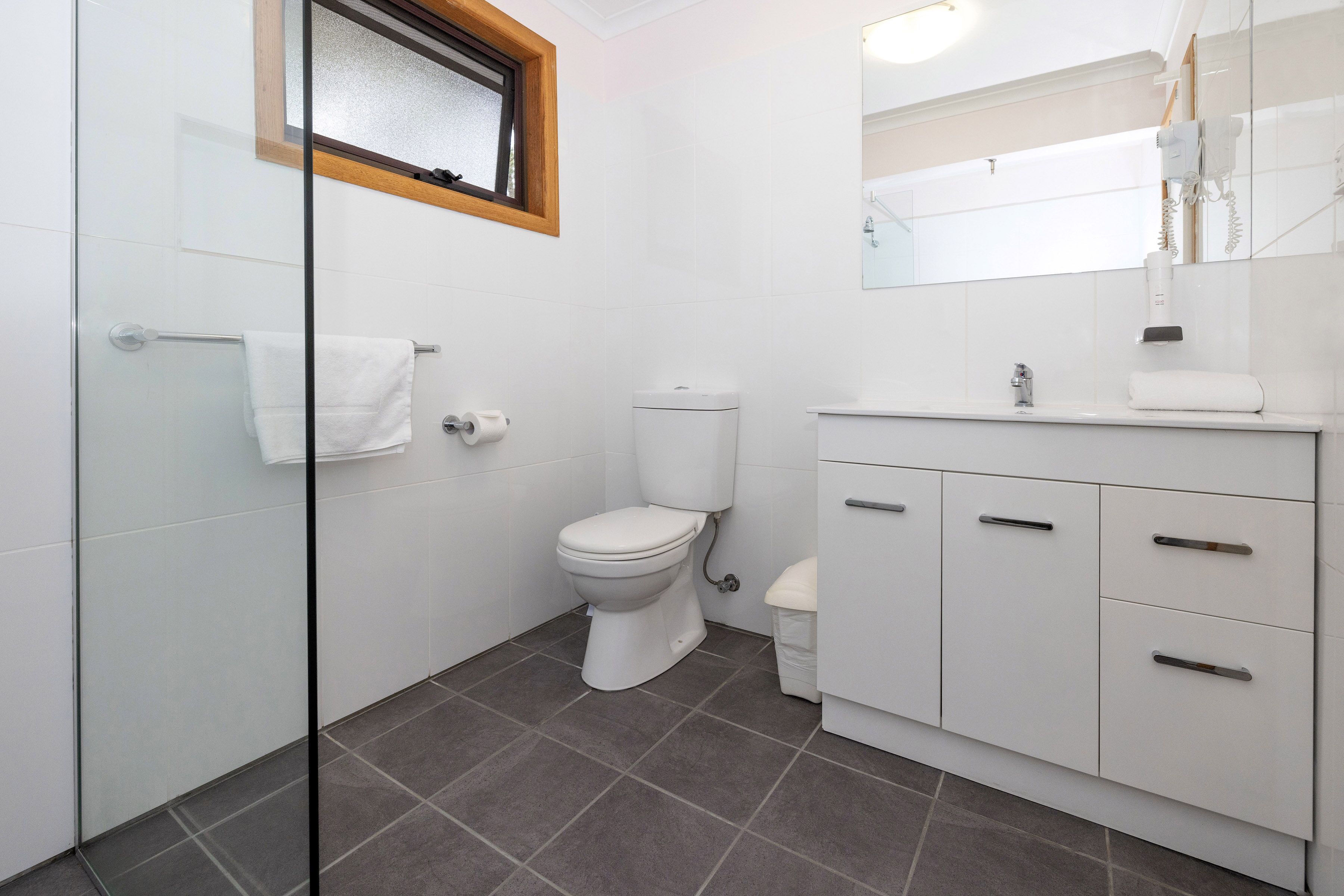 Une salle de bain moderne équipée de toilettes, d’un lavabo et d’une douche à parois de verre.