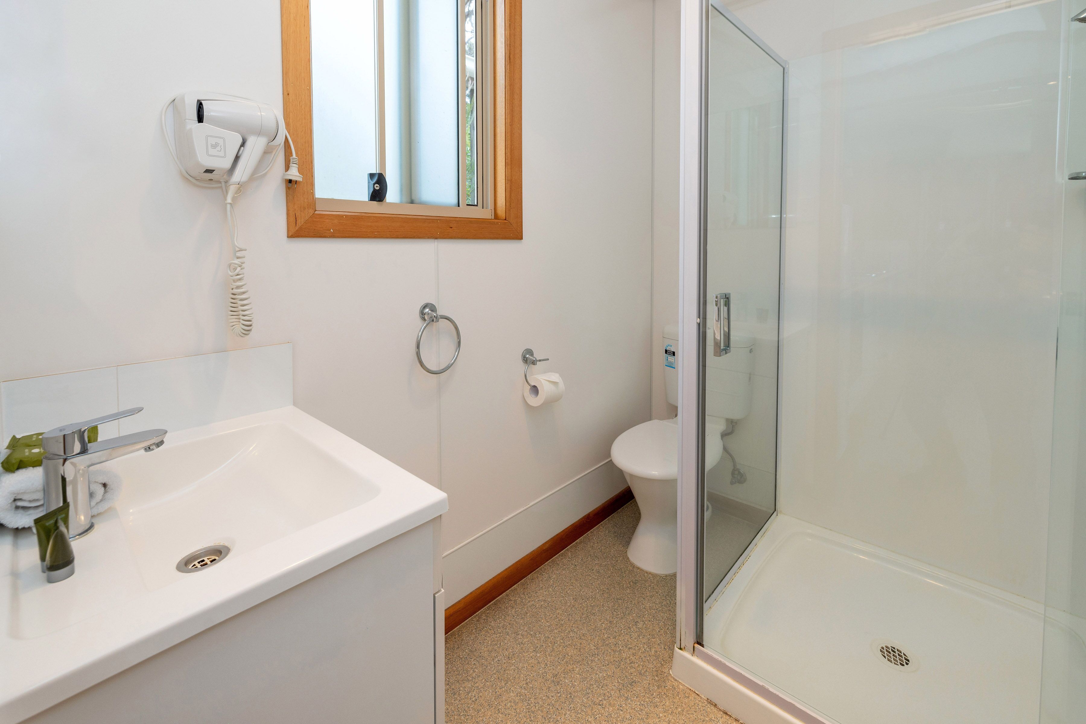A bathroom with a white sink, a mirror, a toilet, and a glass-enclosed shower.