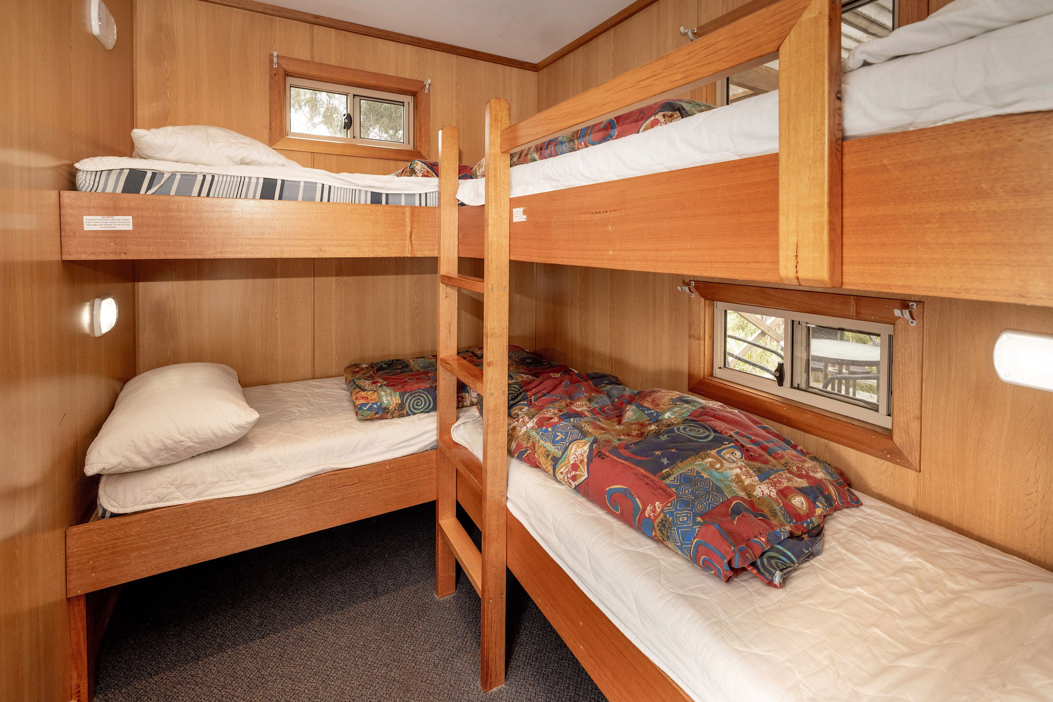 A bunk bed room with wooden walls and a window.