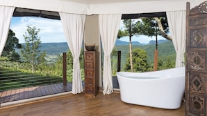 A room with a wooden deck, a white bathtub, and a view of a mountainous landscape. - Clouds on Beechmont (Beechmont)