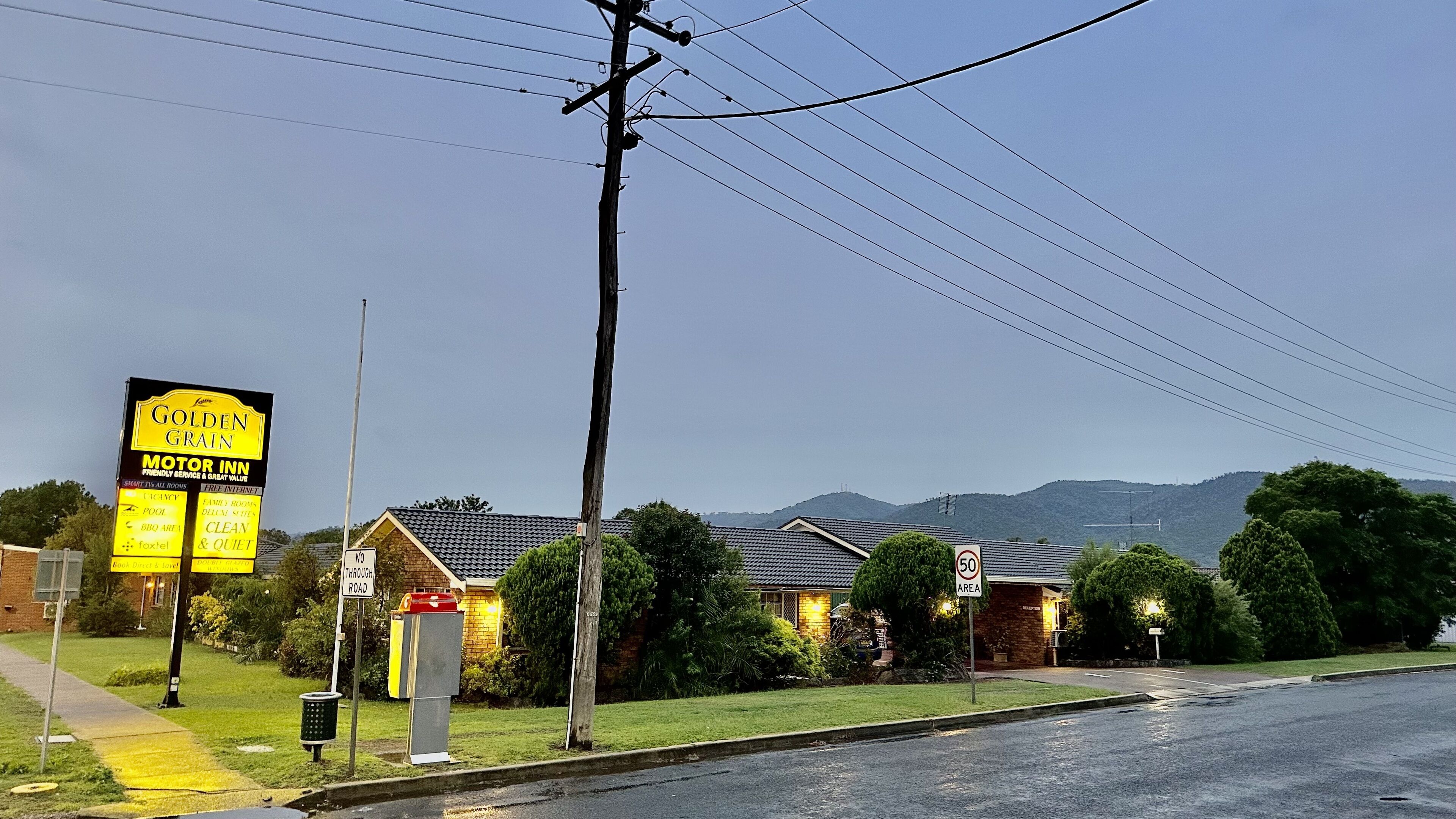 A motor inn with a signboard advertising amenities like a pool, BBQ area, and clean & quiet rooms.
