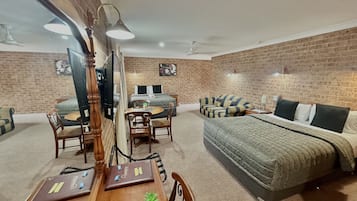 Una habitación con pared de ladrillo, cama, sofá, mesa de comedor con sillas y televisor.