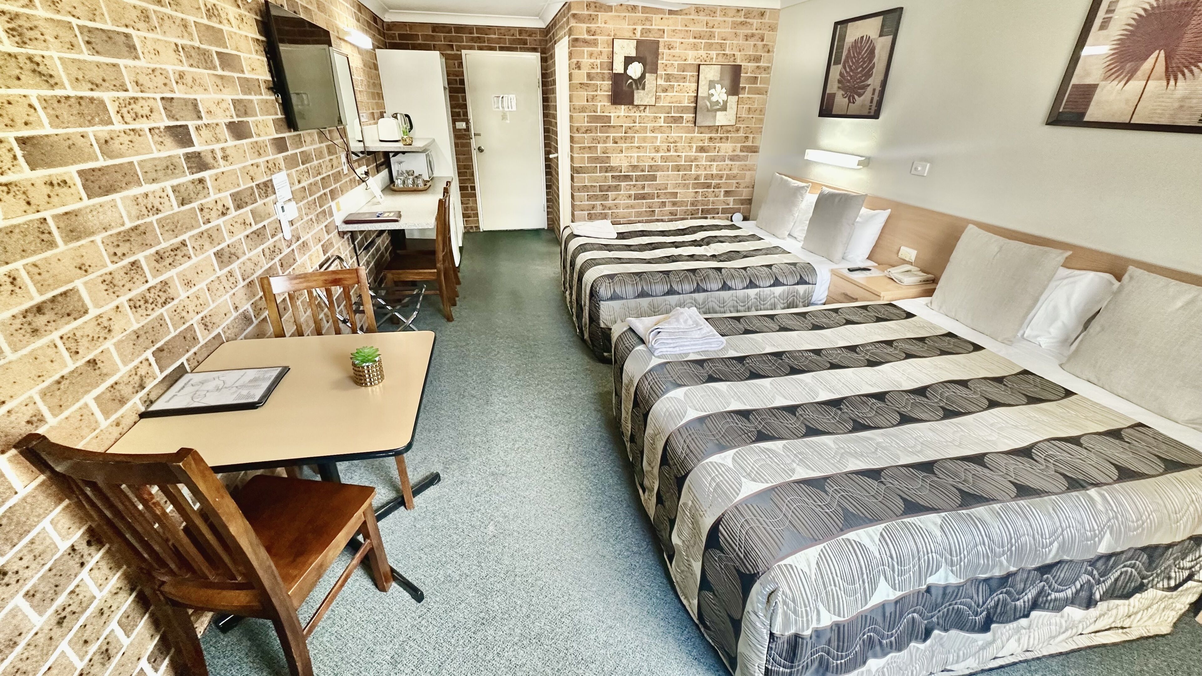 A hotel room with three beds, a desk, and a chair.