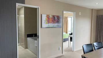 Una habitación de hotel moderna con baño, zona de comedor y un cuadro en la pared.