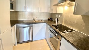 A modern kitchen with white cabinets, stainless steel appliances, and a granite countertop. - Alpha Motel Christchurch (Christchurch)