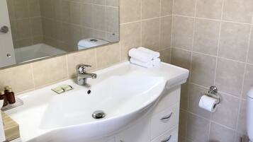 A bathroom with a white sink, mirror, and toilet. There is a framed sign on the wall and a towel rack above the sink.
