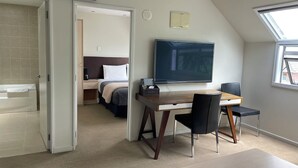 A modern hotel room with a large bed, a desk with a chair, a flat-screen TV, and a skylight. - Alpha Motel Christchurch (Christchurch)