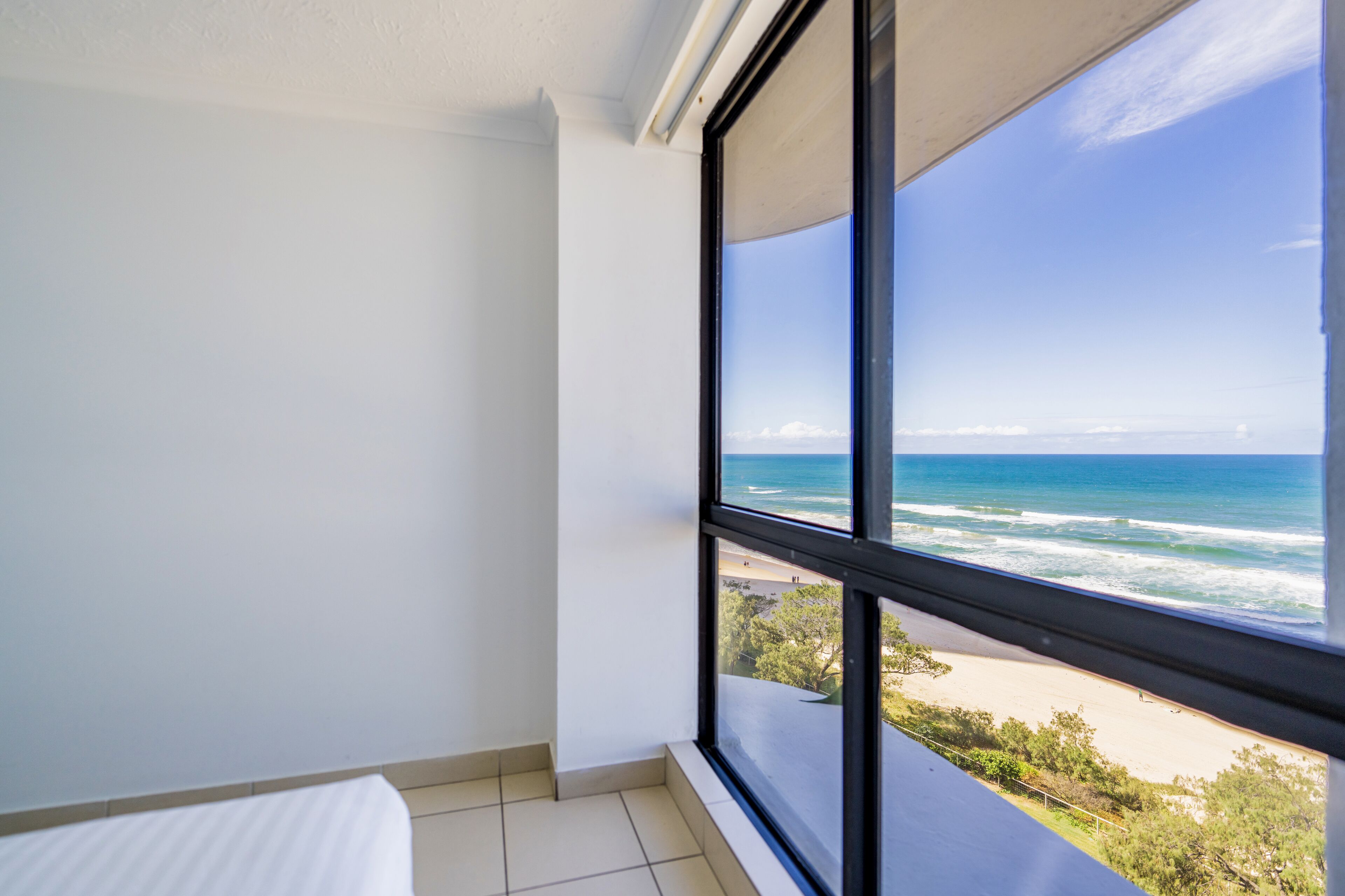 A room with a large window overlooking a beach and ocean.