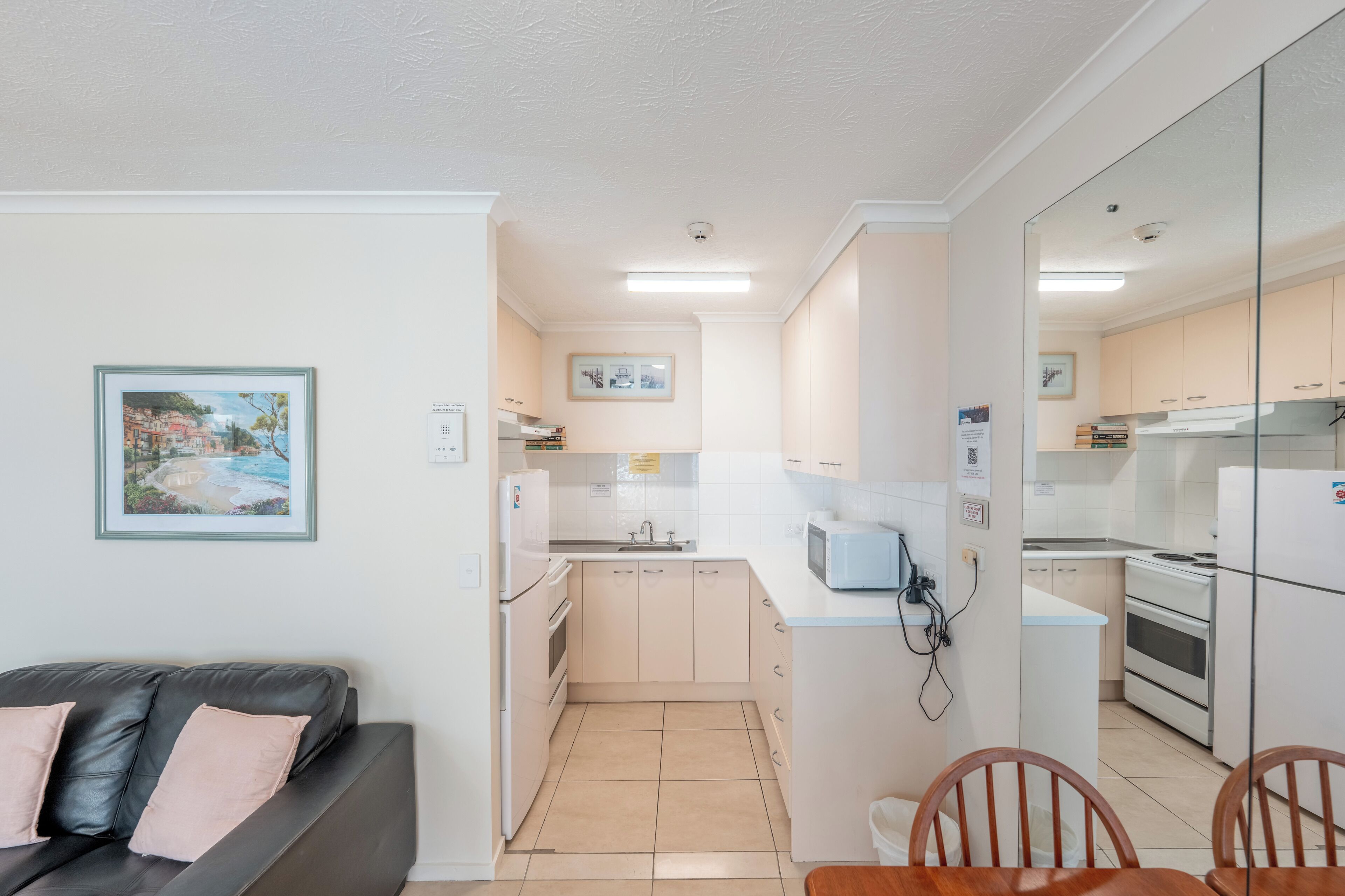 Un espacio habitable pequeño con kitchenette, sofá y zona de comedor.
