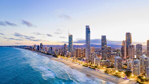 A coastal cityscape with high-rise buildings along a beach, featuring a mix of modern architecture and waterfront views.