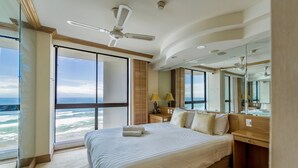 A spacious bedroom with a large bed, a desk, and a view of the ocean.