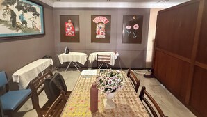 A dining area with a table set for four, chairs, a vase of flowers, and three framed artworks on the wall.