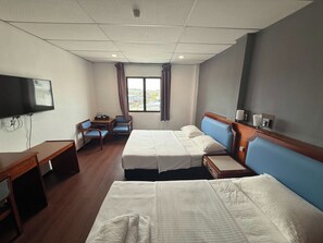 Habitación de hotel con dos camas, un escritorio, un televisor y una ventana con cortinas.