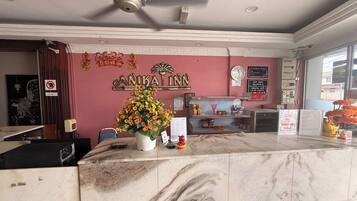 A reception area with a marble counter, a ceiling fan, a clock, and a wall with a sign that reads "ANKAT INN".