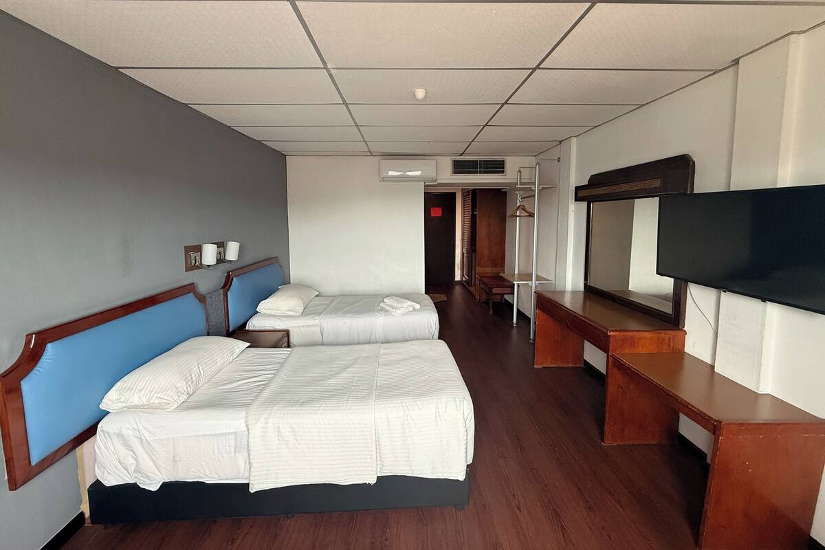 A hotel room with two beds, a TV, a desk, and a wardrobe.