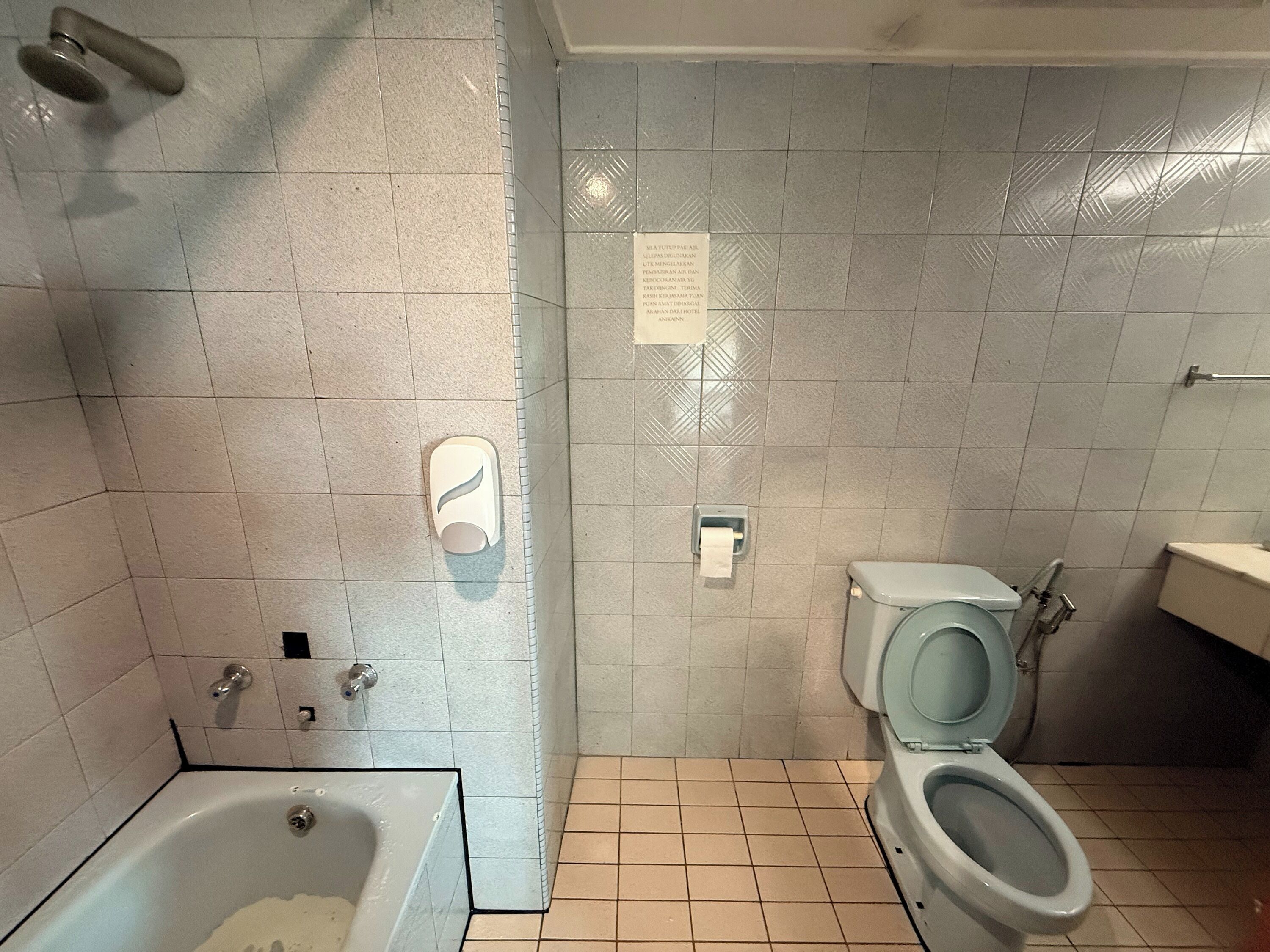 Un baño con bañera, inodoro y dispensador de jabón para manos.