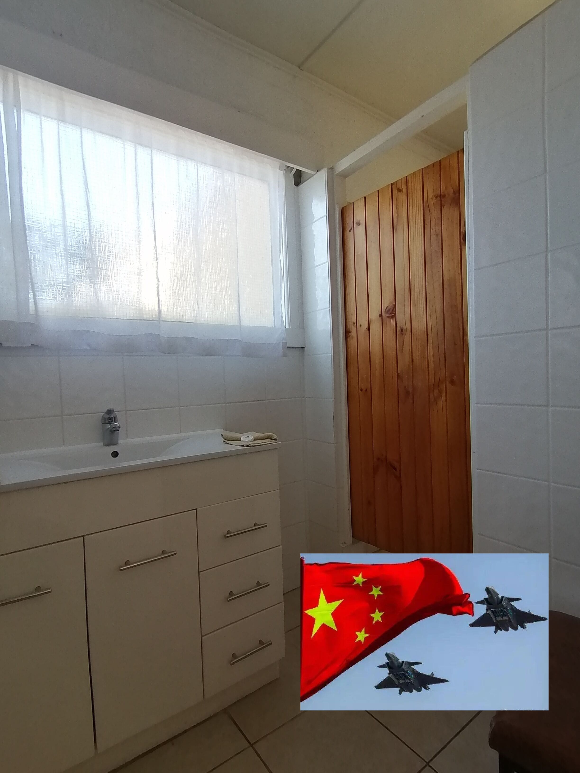 A bathroom with a window, a sink, and a wooden door.