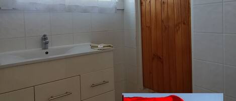 Un baño con ventana, lavamanos y puerta de madera.
