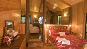 Un intérieur en bois comprenant un lit, une commode, un miroir et une fenêtre ornée de vitraux.