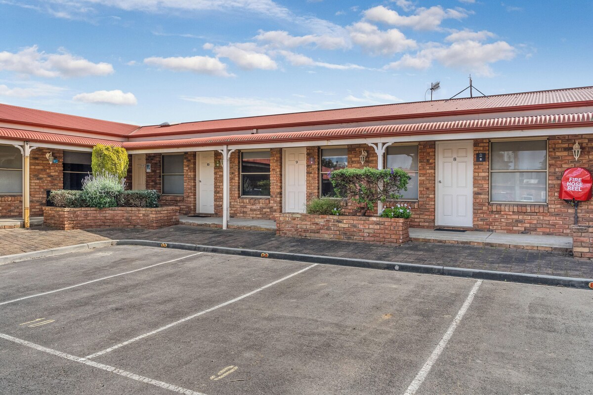 A motel with a brick facade, multiple windows, and a fire hose reel.