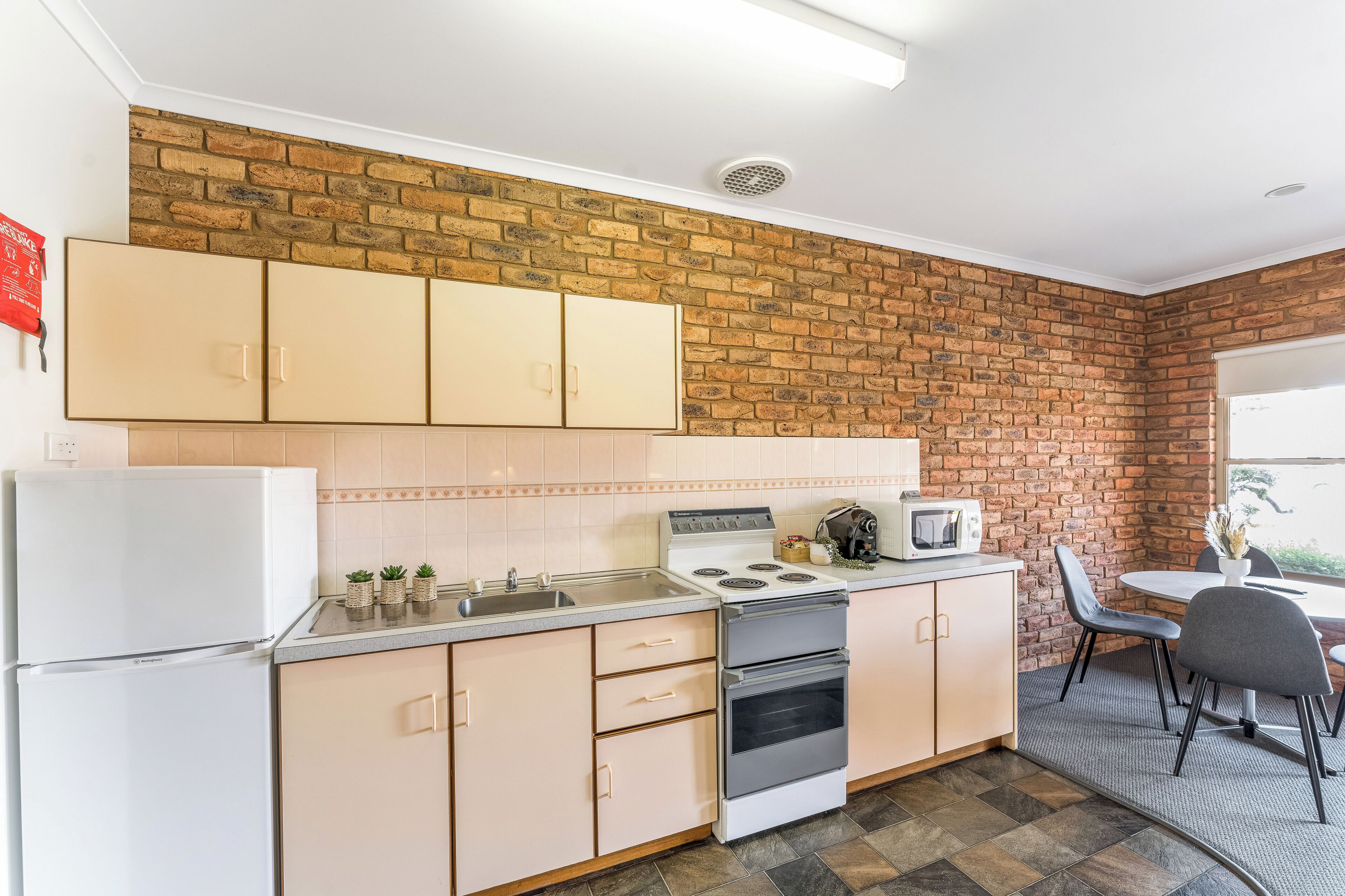 A kitchen with beige cabinets, a white refrigerator, a stove, and a microwave.