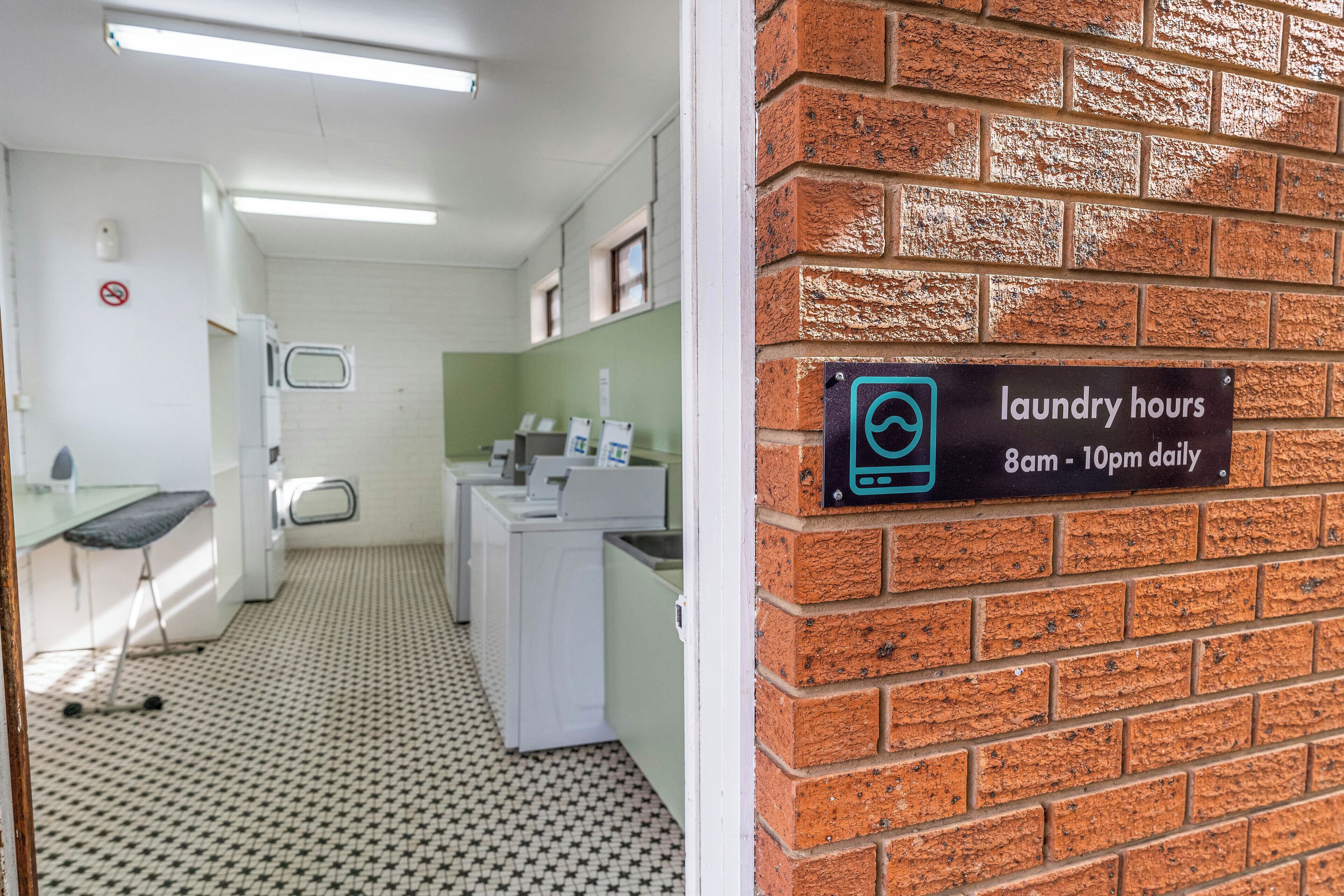 A laundry area with a sign indicating laundry hours from 8am to 10pm daily.