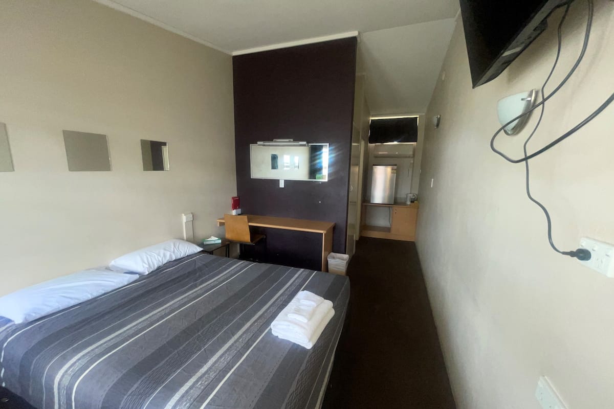 Ein Hotelzimmer mit Bett, Schreibtisch, Fernseher und Spiegel.