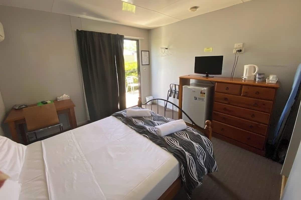 Ein Hotelzimmer mit Bett, Schreibtisch, Kommode, Fernseher und Kühlschrank.