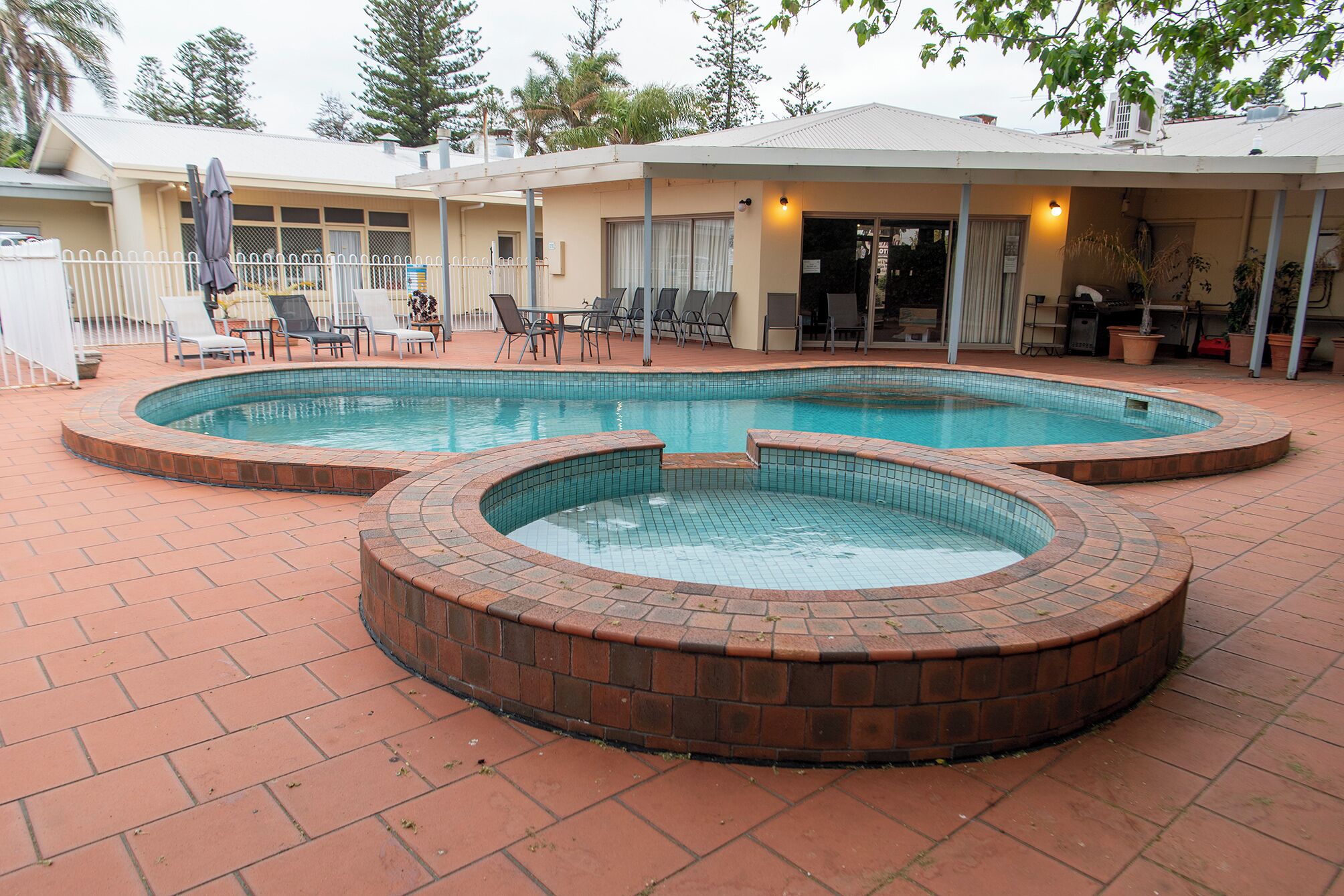 Un área de piscina con dos jacuzzis y una zona de estar cubierta con sillas y mesas.