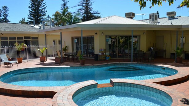 A swimming pool with a brick border and a sun deck area with chairs and tables. - Glenelg Motel (Glenelg North)