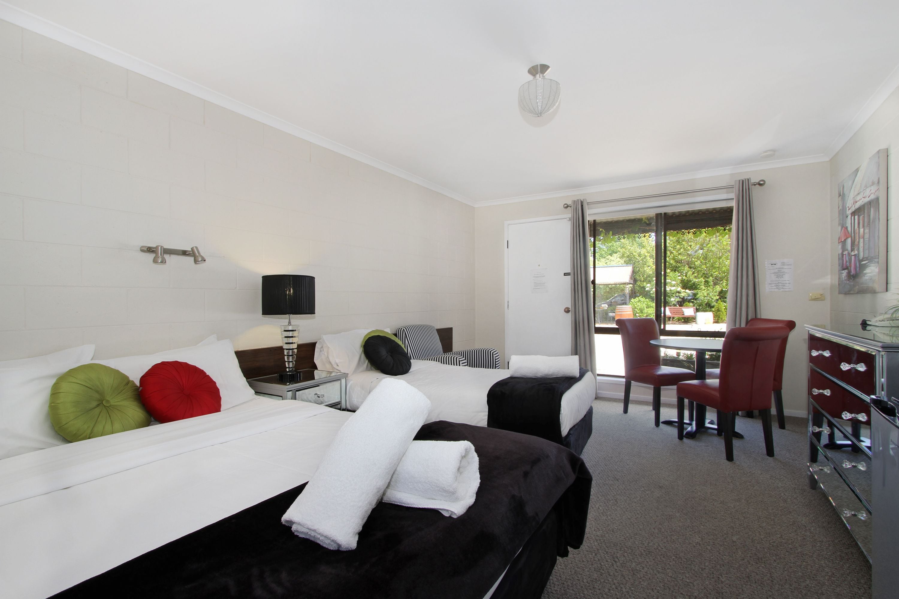 Habitación de hotel con dos camas, un escritorio, una silla y vistas al exterior.