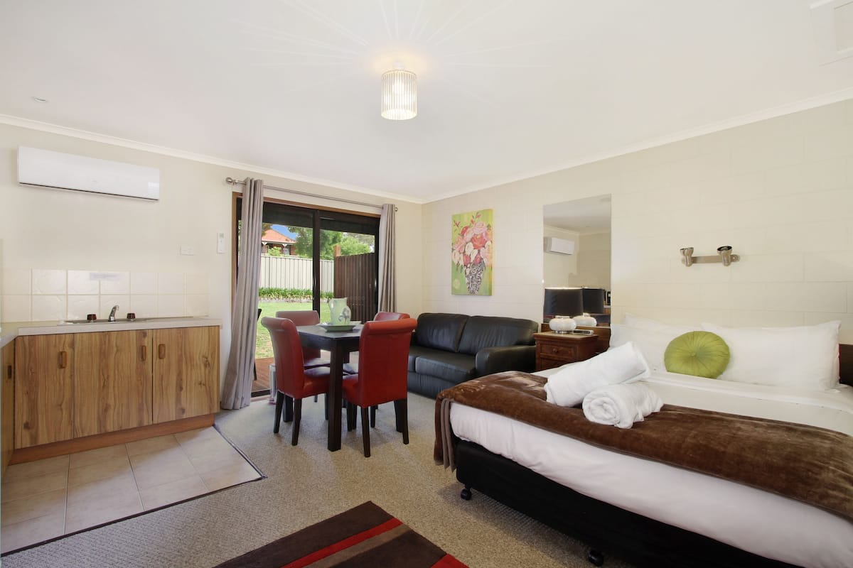 Una habitación de hotel con cama, escritorio, silla, sofá, mesa de comedor y ventana.