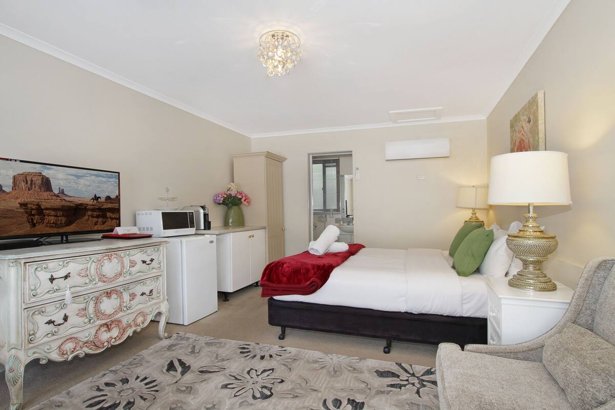 Habitación de hotel con cama, televisión, escritorio, microondas y lámpara.