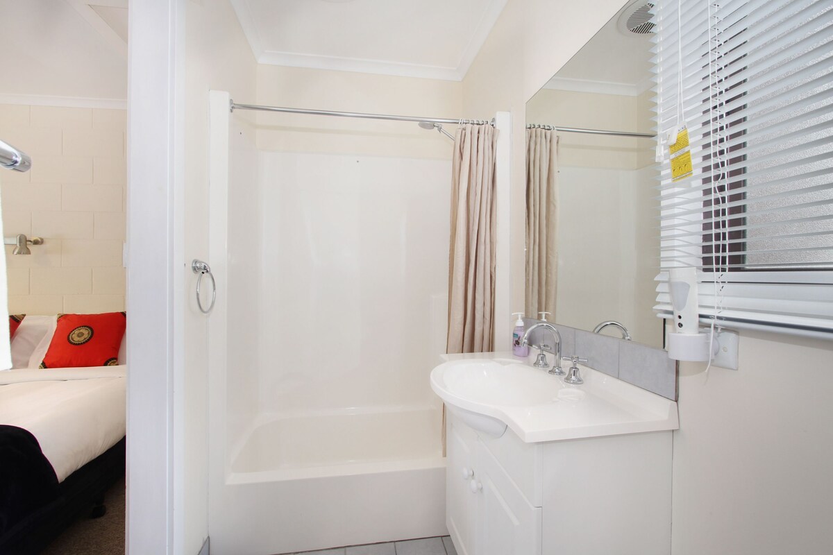 A bathroom with a bathtub, a shower, a sink, and a mirror.