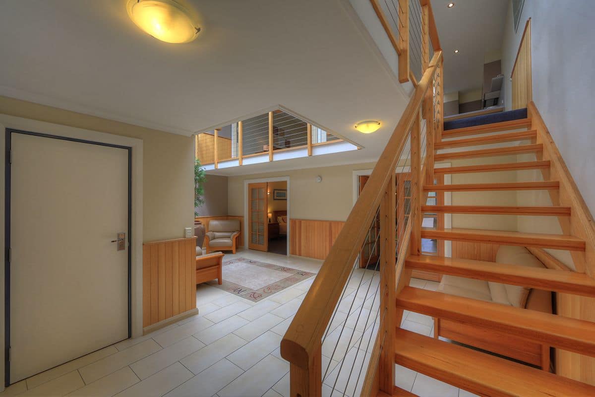 Un intérieur spacieux avec un escalier en bois, un plafond haut et une vue dégagée grâce à une lucarne.