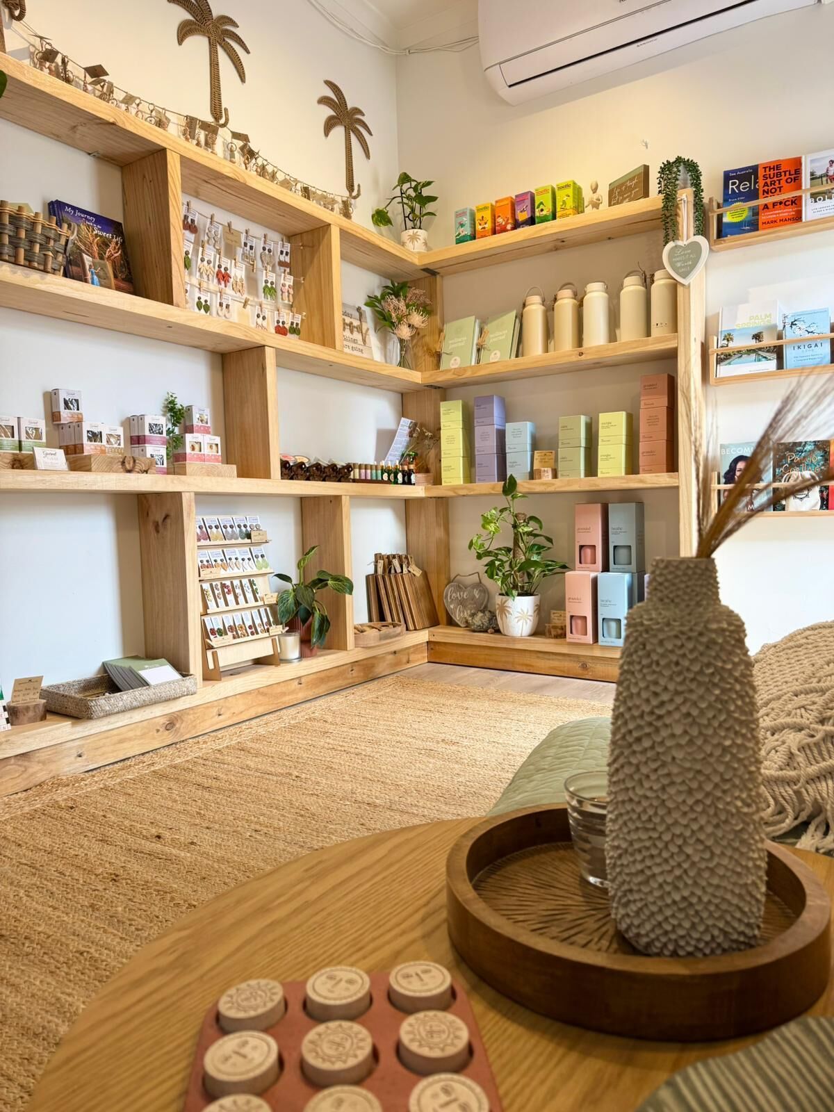 Una habitación bien organizada con estanterías de madera que exhiben diversos objetos, una planta pequeña y un jarrón decorativo sobre una mesa de madera.